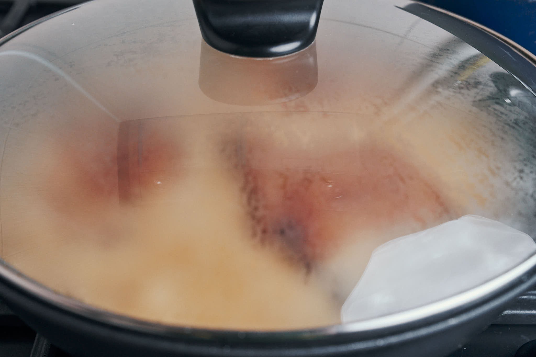 pork chops simmering in creamy mushroom sauce under a lid