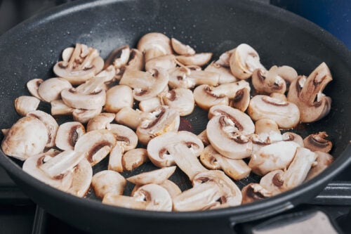 sliced mushrooms cooking in a skillet