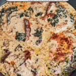 Creamy Tuscan chicken cooked in a skillet with sun-dried tomatoes, spinach, and parmesan cream sauce