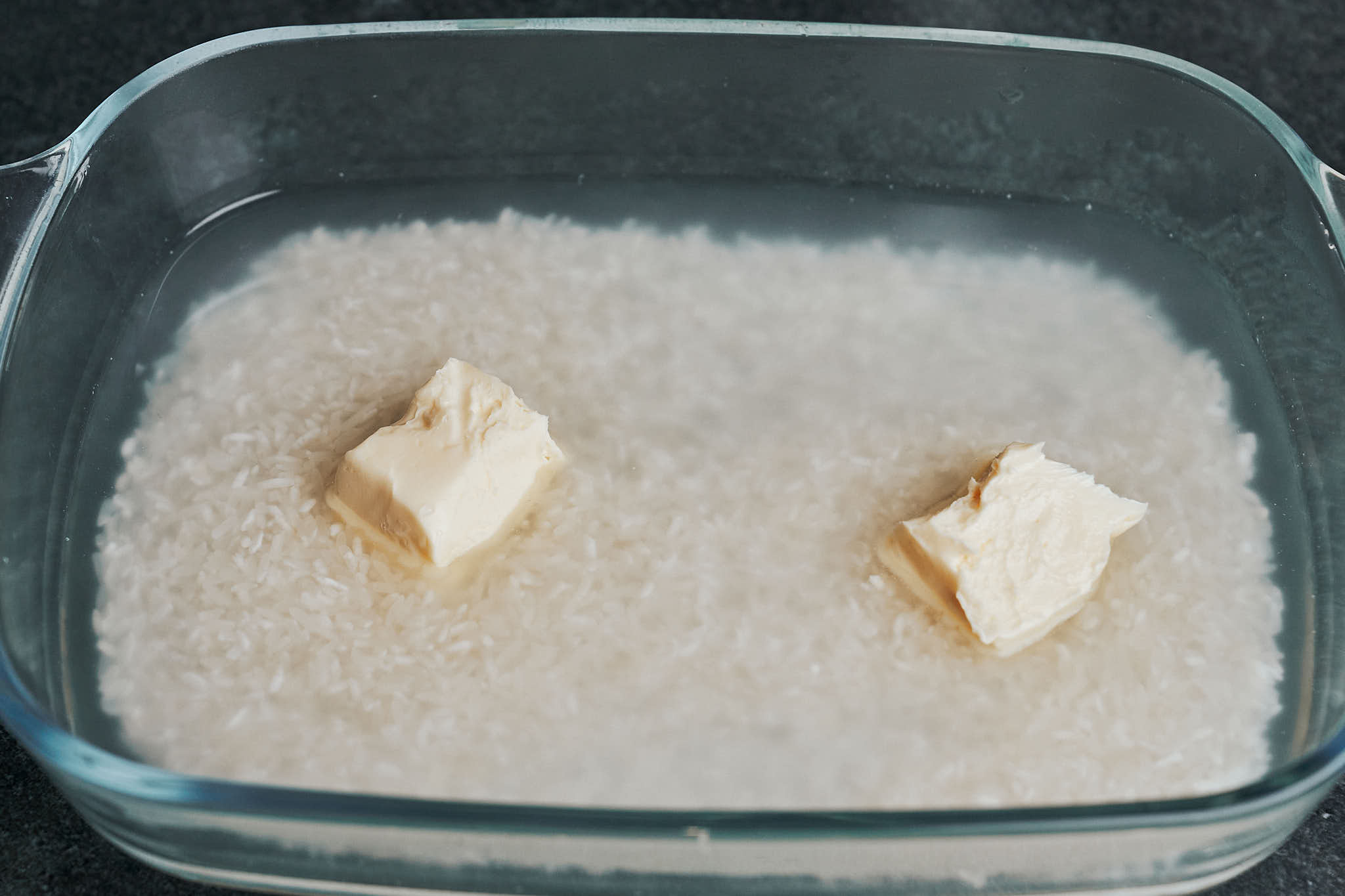adding water and butter to rice before baking
