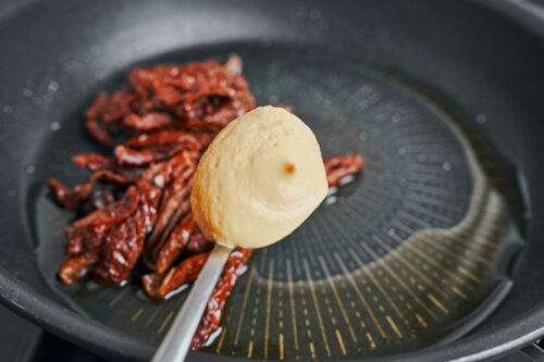 Dijon mustard added to sun-dried tomatoes in a skillet