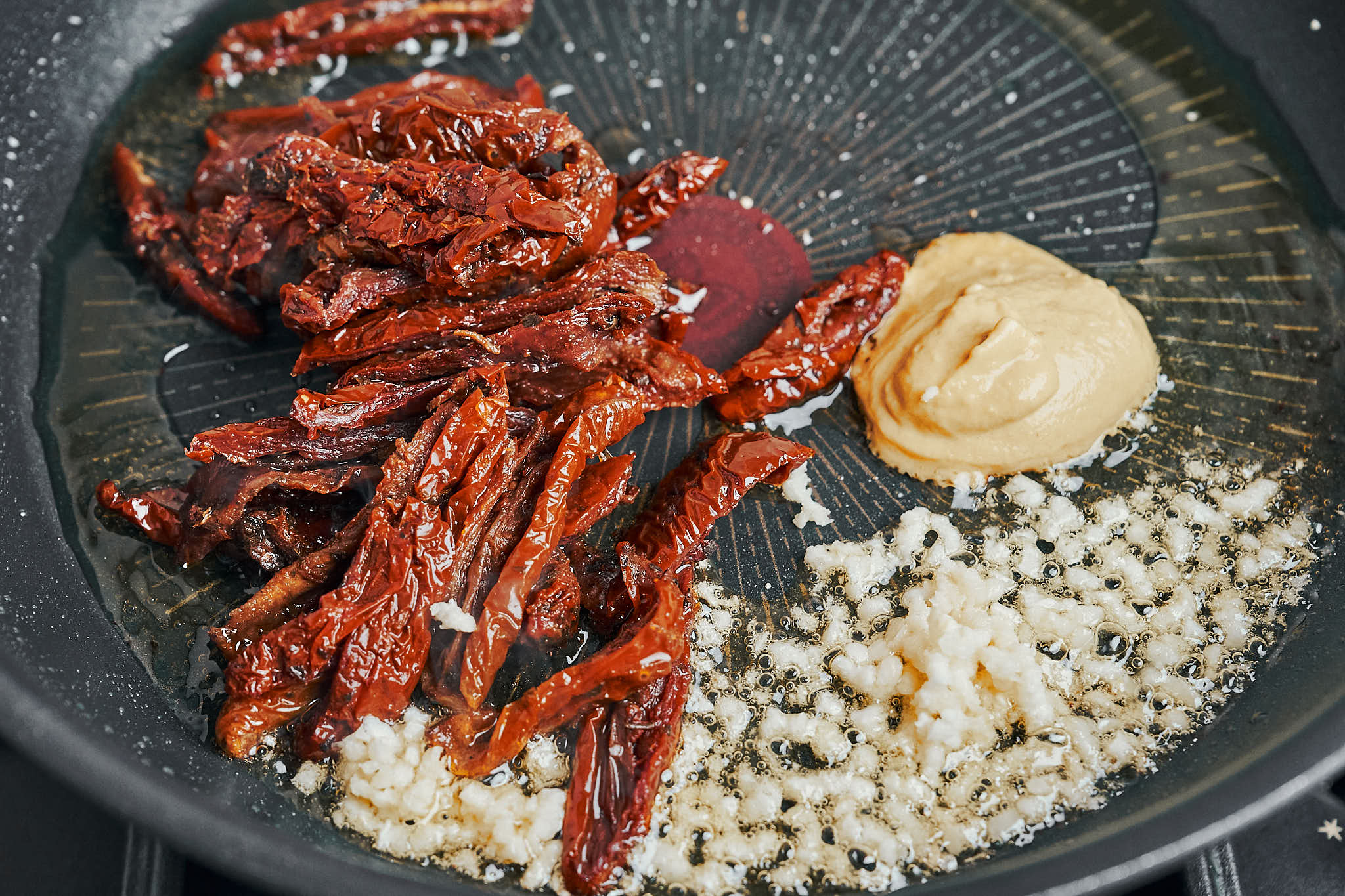 Sun-dried tomatoes, garlic, and Dijon mustard cooking in a skillet