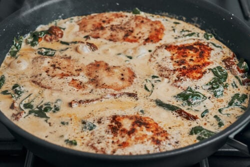 Chicken cutlets simmering in creamy Tuscan sauce with spinach