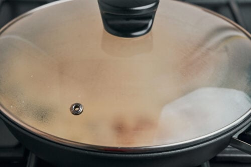 Skillet covered with a lid while the chicken finishes cooking
