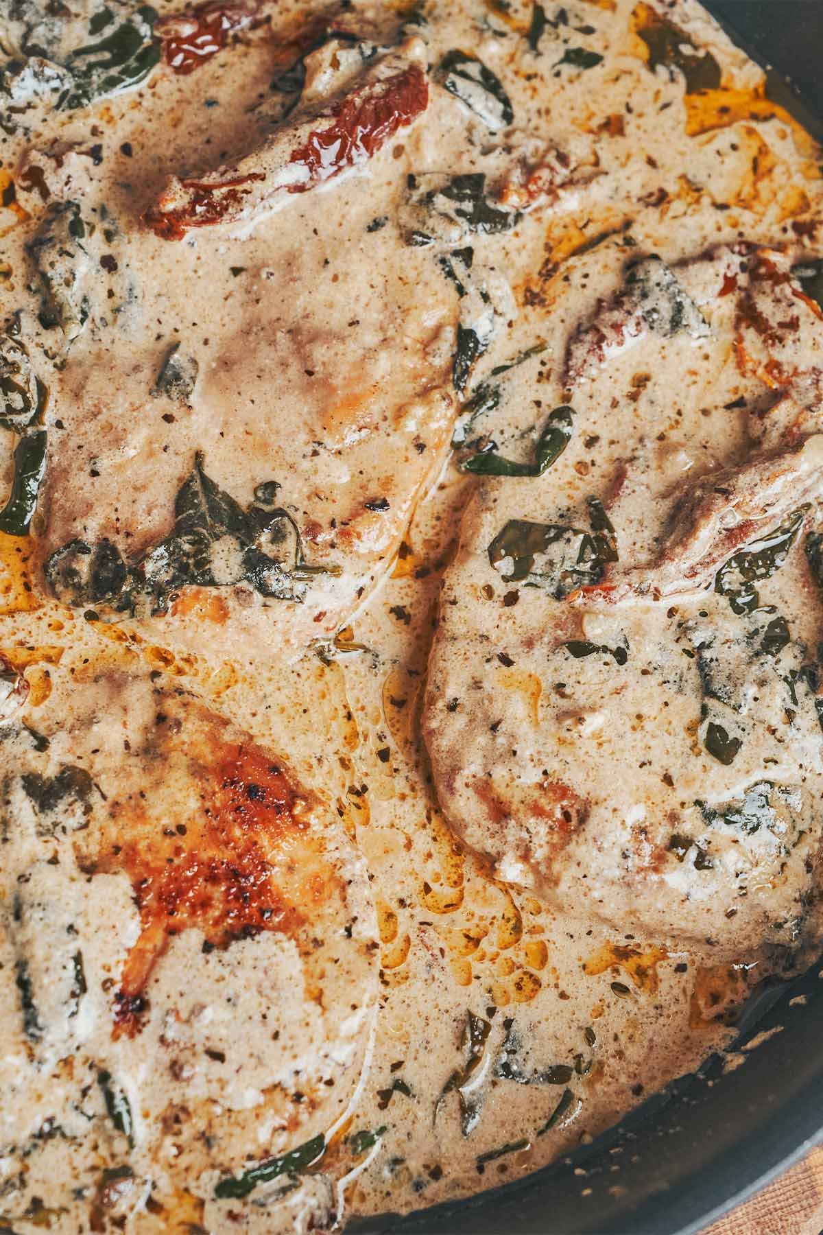Creamy Tuscan chicken cooked in a skillet with sun-dried tomatoes, spinach, and parmesan cream sauce