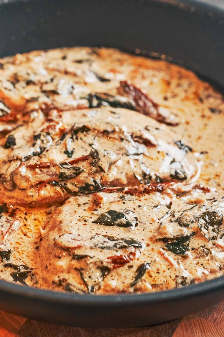 Creamy Tuscan chicken breasts in a skillet with sun-dried tomatoes, spinach, and garlic Parmesan cream sauce