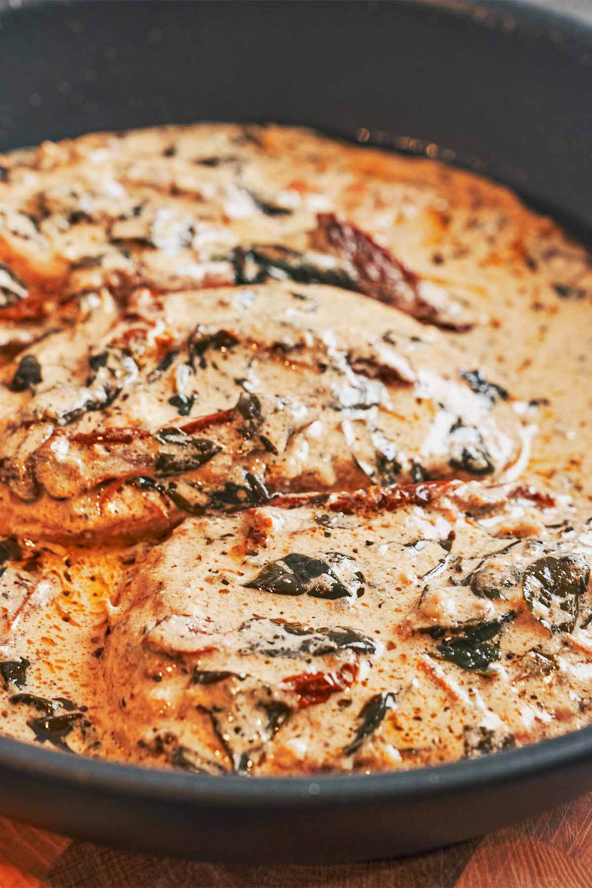 Creamy Tuscan chicken breasts in a skillet with sun-dried tomatoes, spinach, and garlic Parmesan cream sauce
