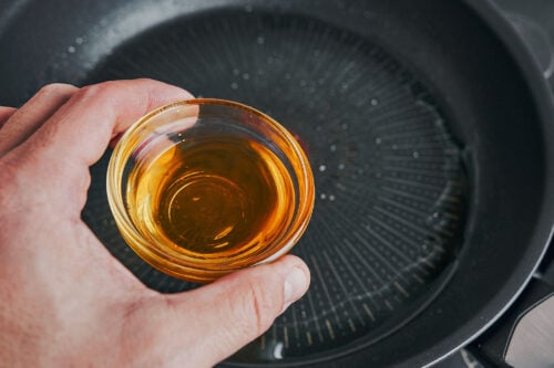 Sun-dried tomato oil being added to a skillet