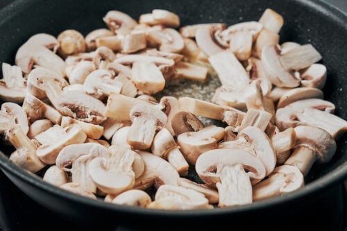 adding mushrooms to butter in a skillet