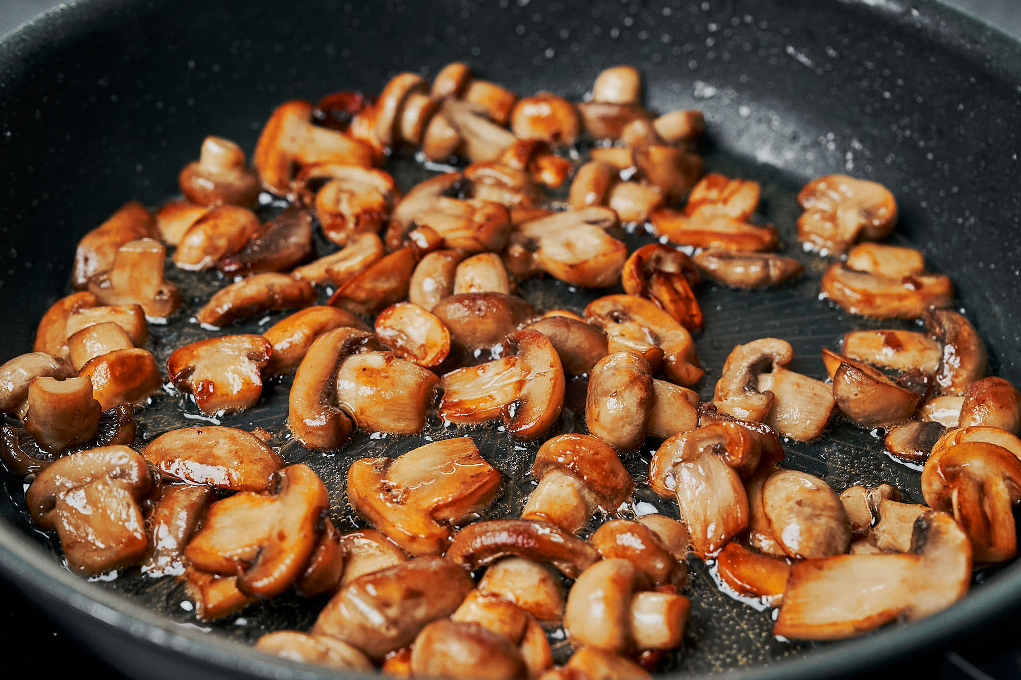 golden mushrooms cooking in butter in a skillet