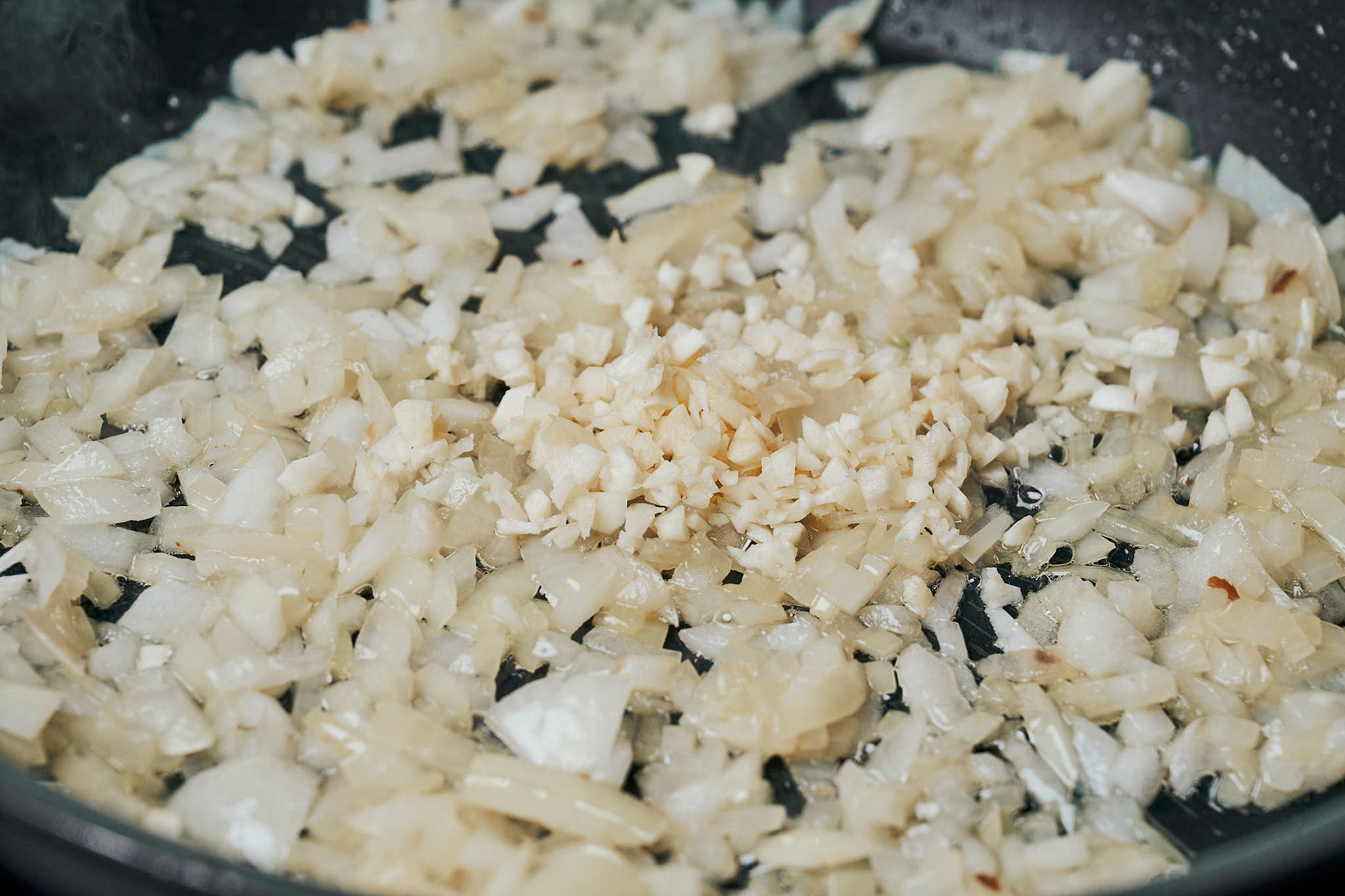 chopped onions cooking with garlic in a skillet