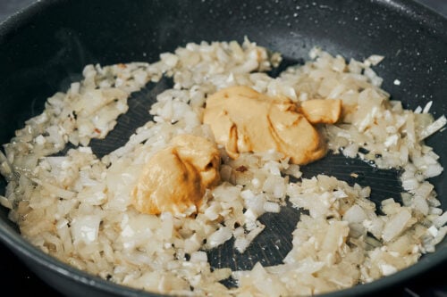 Dijon mustard mixed into onions in a skillet