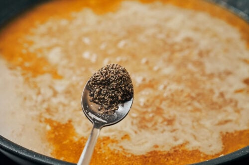 adding black pepper to the sauce