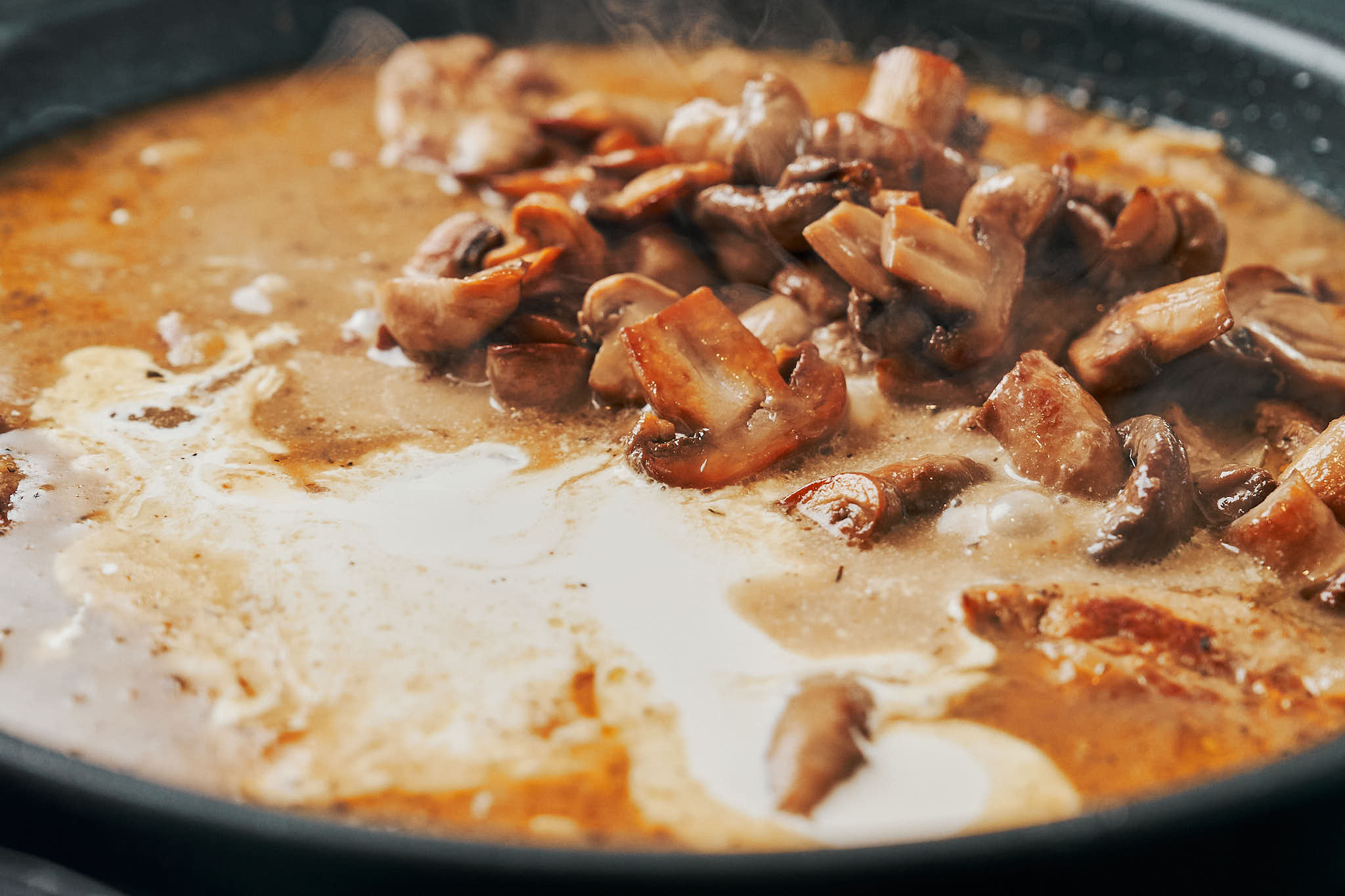 adding sautéed mushrooms to creamy cognac pork tenderloin sauce