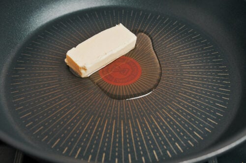 butter melting in a skillet to start creamy parmesan chicken