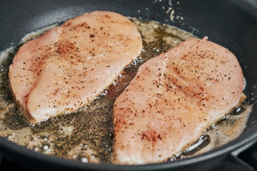 chicken breasts starting to cook in a hot skillet