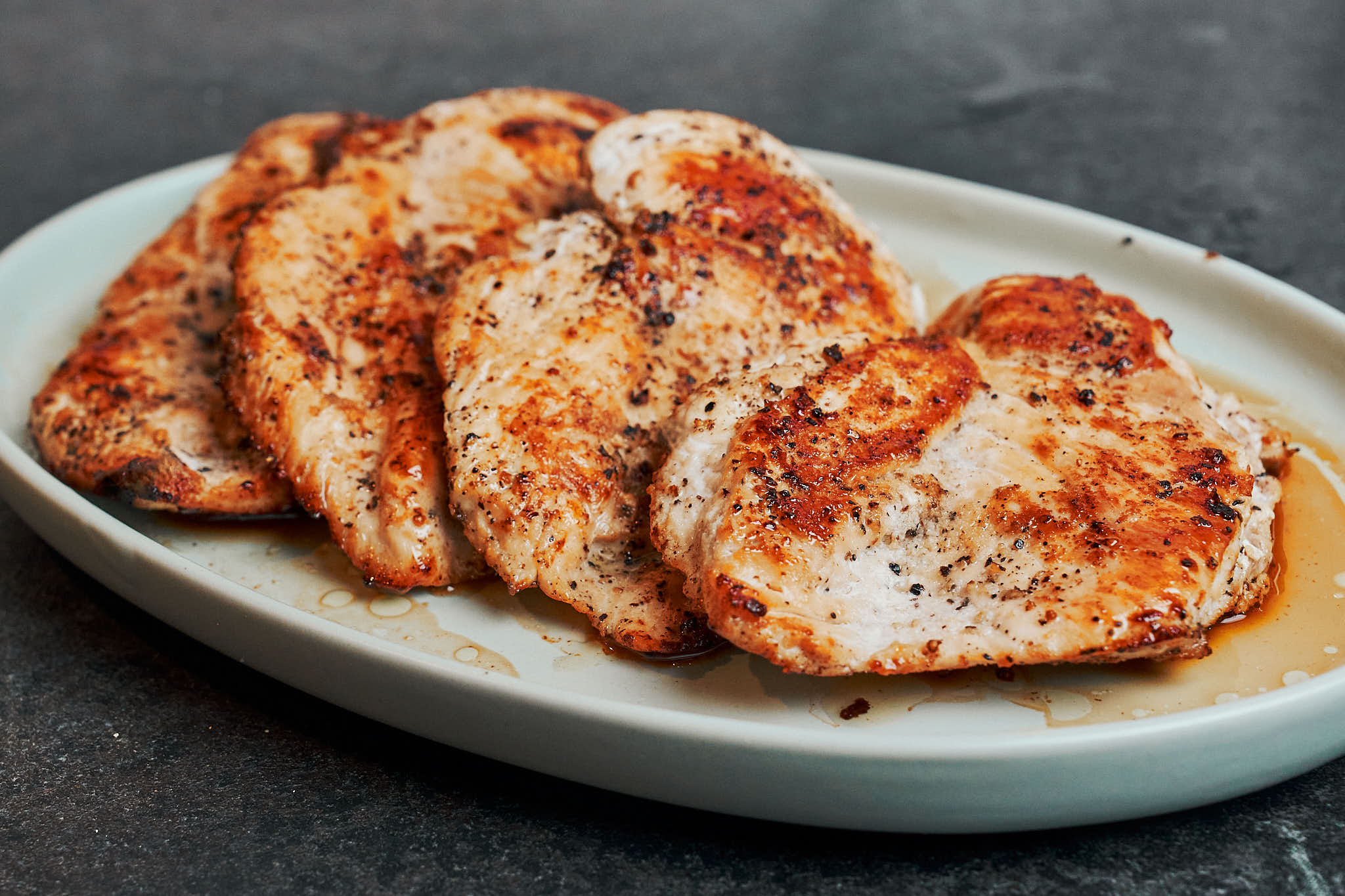 golden pan seared chicken breasts resting on a plate after cooking