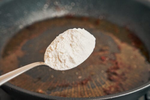adding flour to skillet drippings to begin the creamy parmesan sauce
