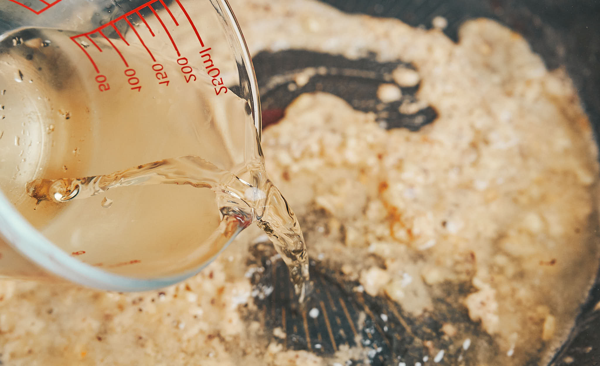 adding chicken broth to the skillet to build the creamy sauce