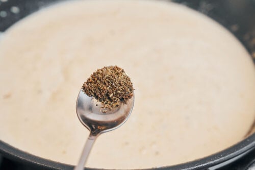 adding thyme to the creamy sauce to build flavor