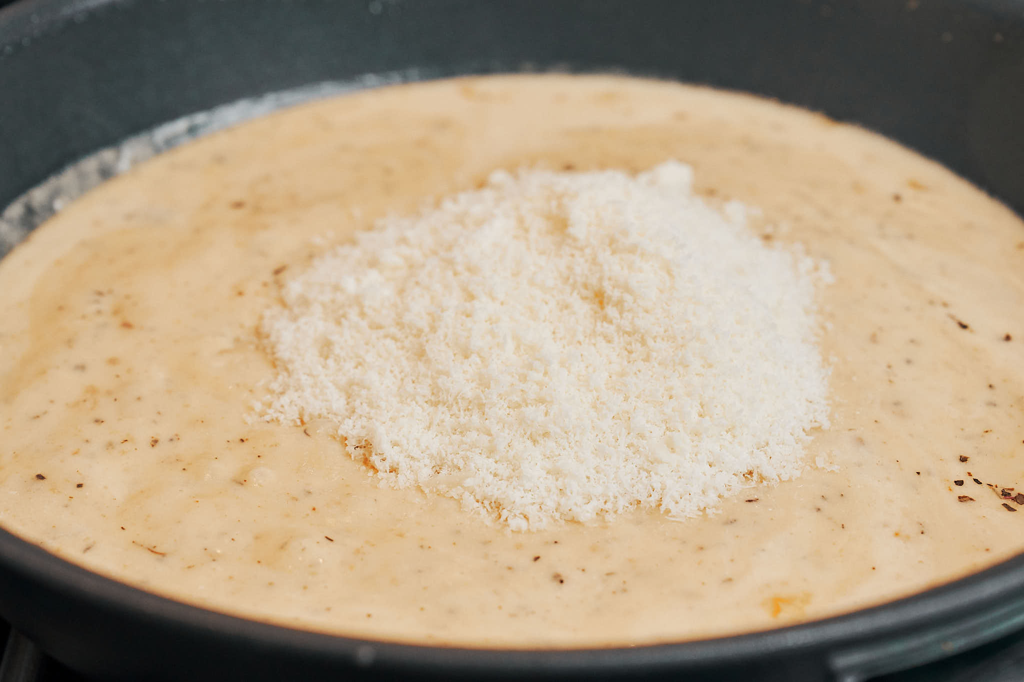 parmesan cheese added to the skillet to create the creamy parmesan sauce
