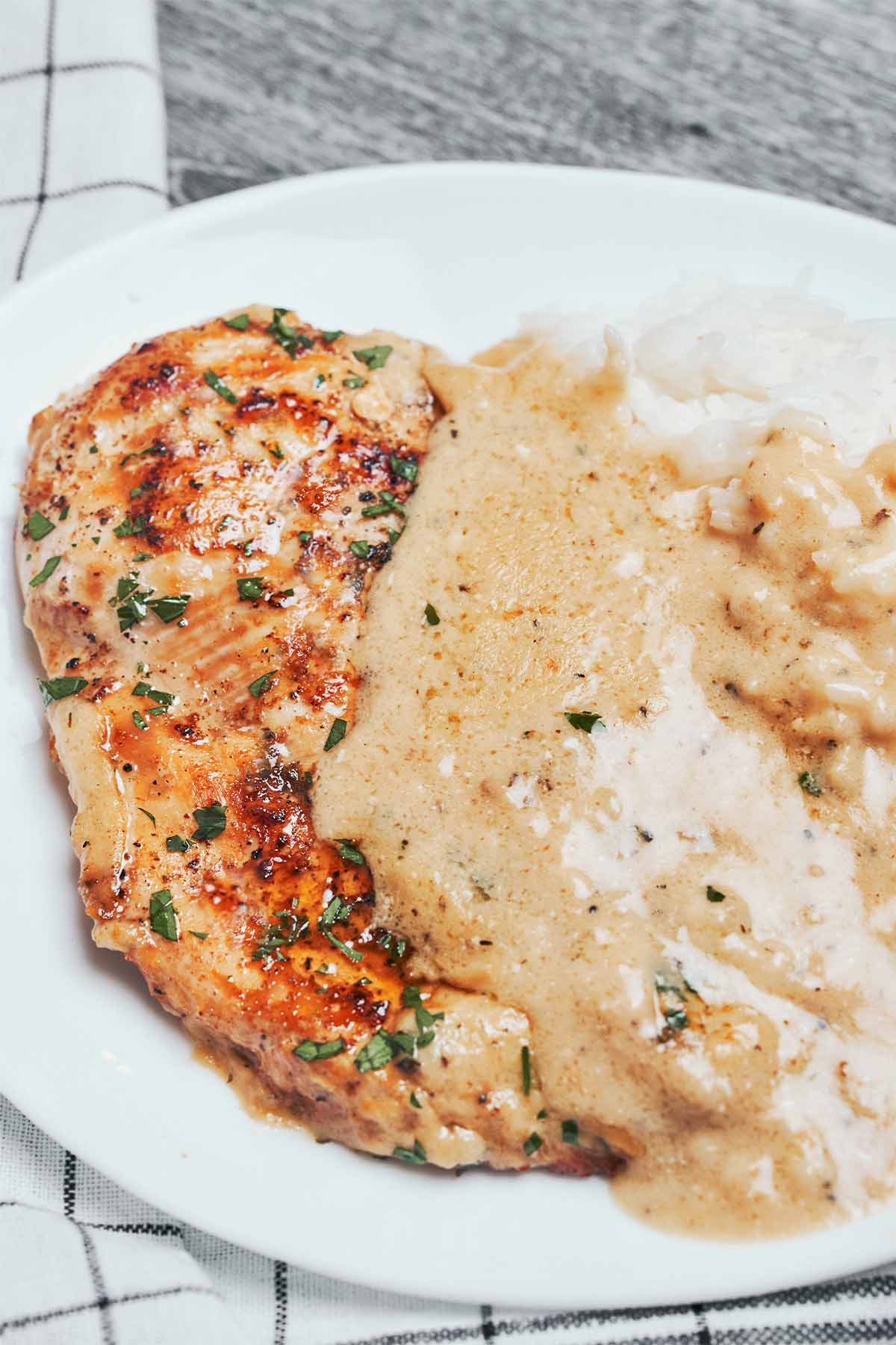creamy parmesan chicken served on a plate with mashed potatoes and rich parmesan sauce