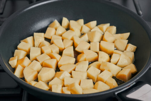 freshly cubed potatoes added to the skillet to start cooking