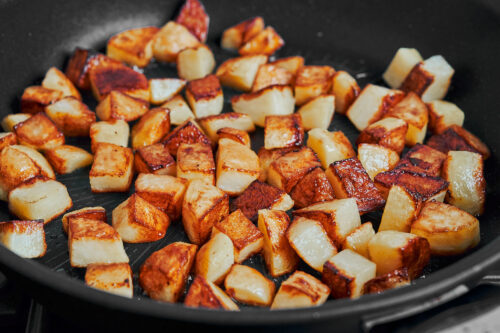 beautifully golden crispy potatoes cooking in the pan