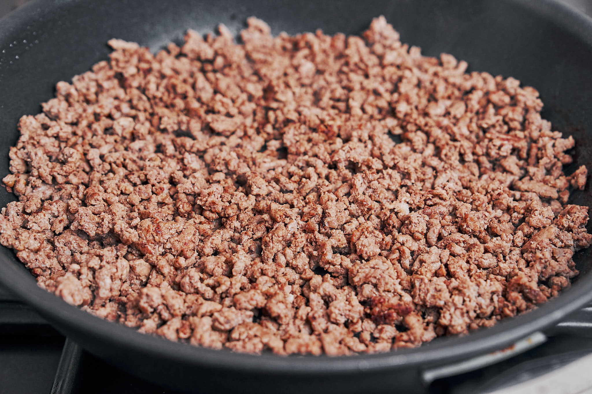 perfectly browned ground beef cooking in the skillet