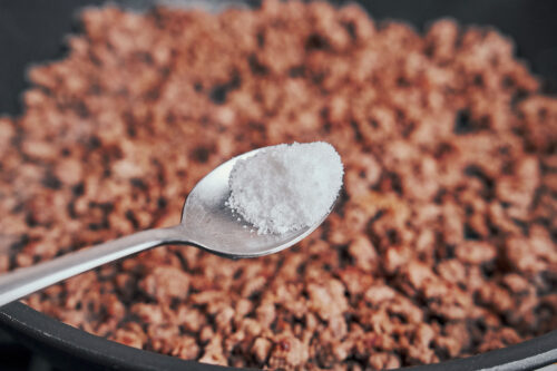 adding salt to browned ground beef in the skillet