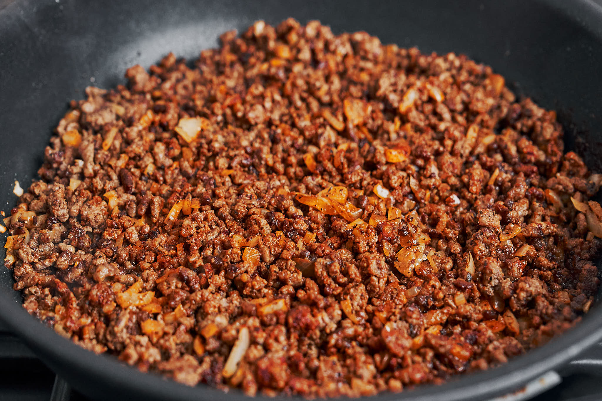 rich and flavorful ground beef cooking with onion and spices in the skillet
