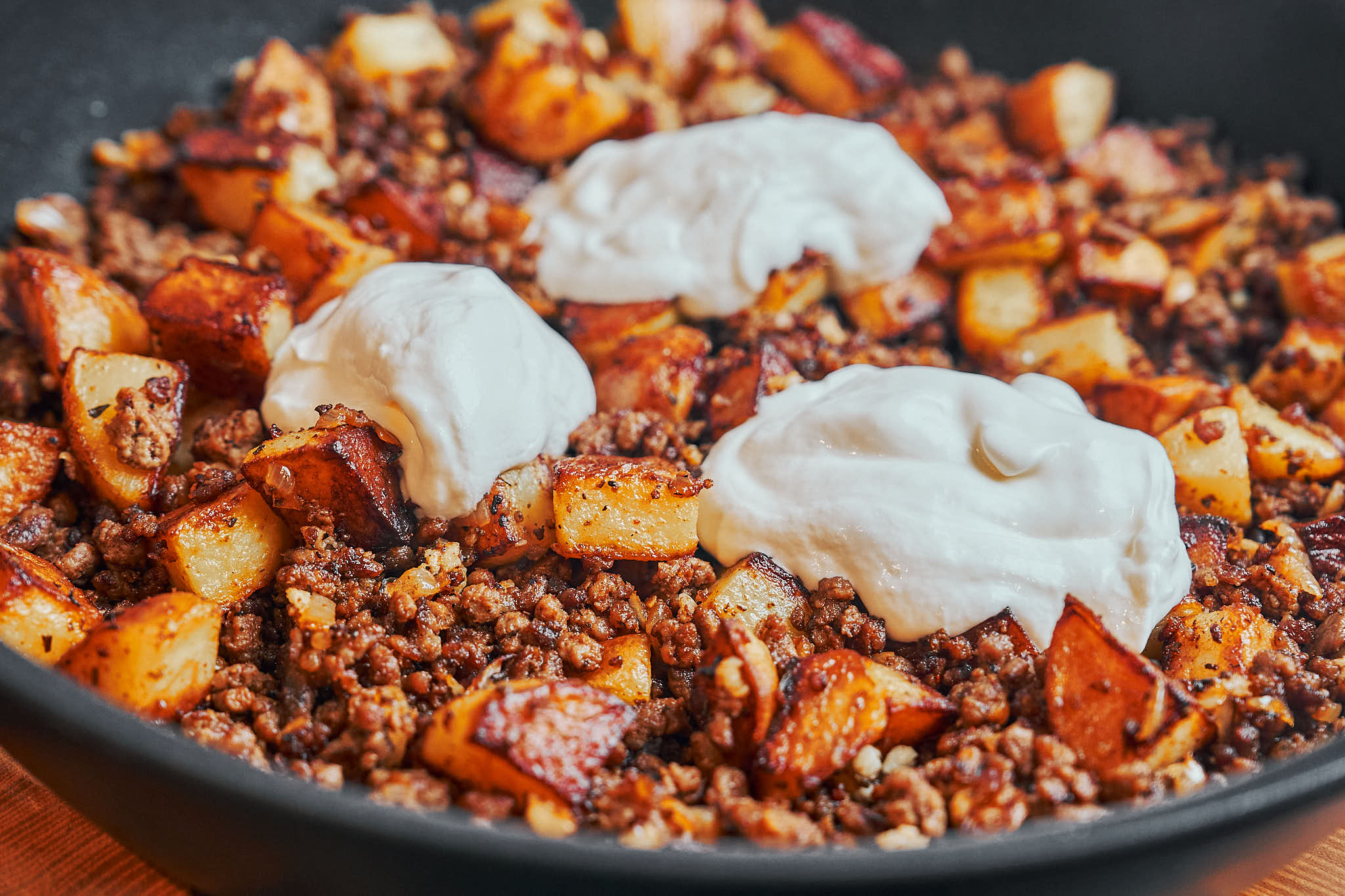 dollops of sour cream melting into the hot ground beef and potatoes