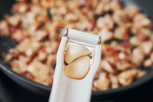 fresh garlic ready to be added to chicken in a skillet