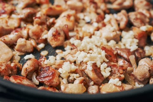 minced garlic added to chicken and onion in a skillet