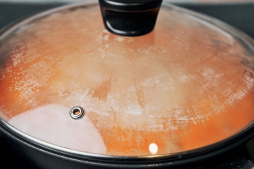 chicken and rice simmering covered in a skillet