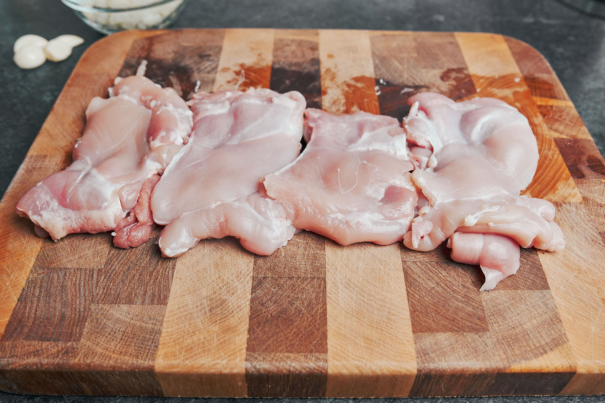 boneless skinless chicken thighs on a wooden cutting board