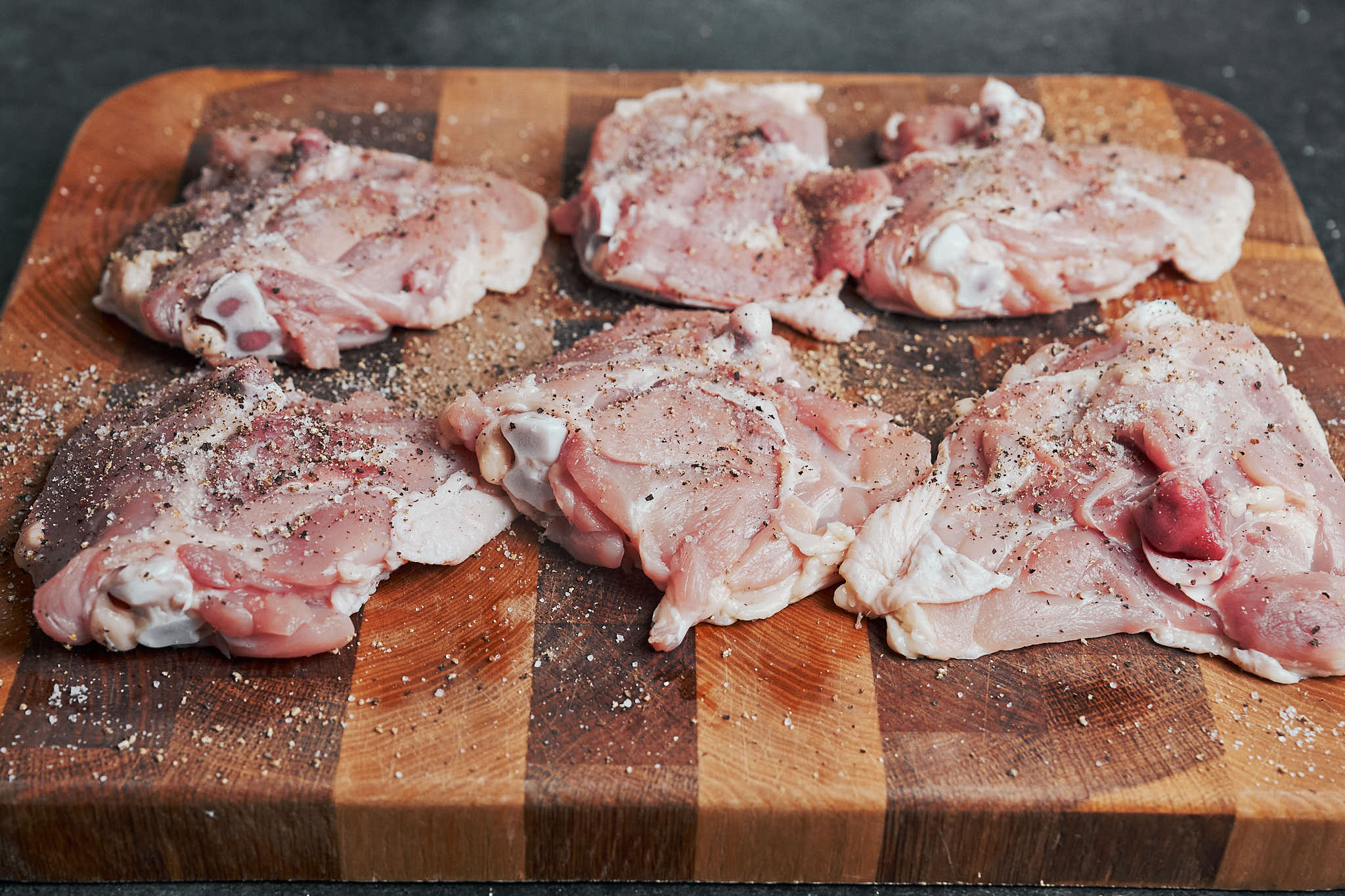 seasoned chicken thighs on cutting board ready for cooking