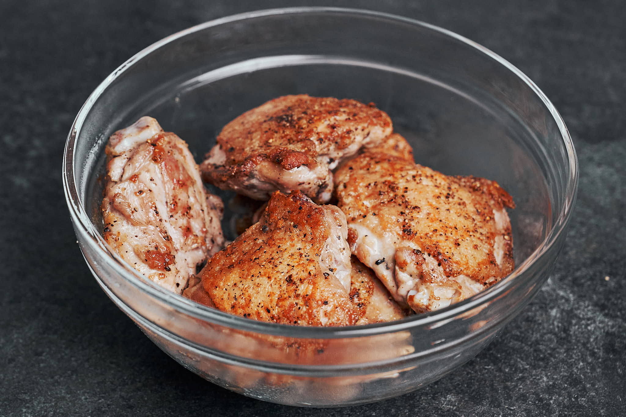 seared chicken thighs resting in bowl after cooking