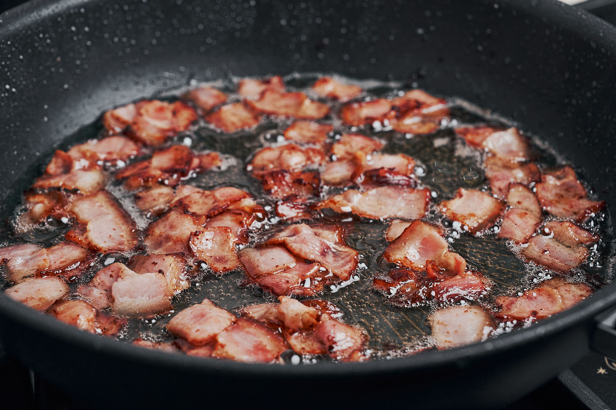 crispy bacon pieces cooking in skillet