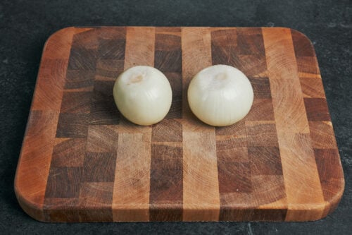 peeled onions on wooden cutting board