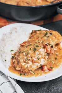 creamy chicken thighs in bacon mustard sauce on plate with rice