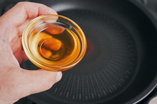 oil being added to skillet before cooking chicken thighs