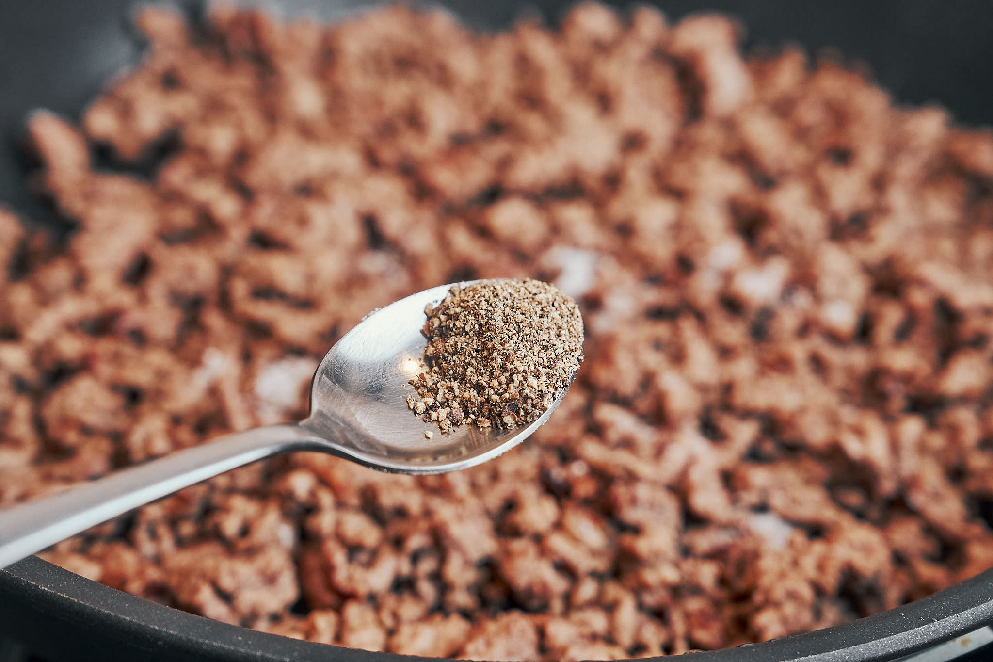 adding black pepper to browned ground beef