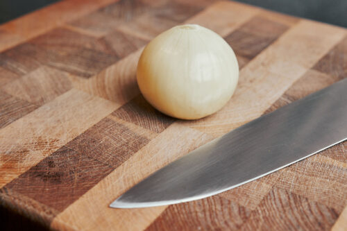 peeled onion on cutting board ready to be diced