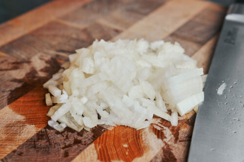 finely diced onion on wooden cutting board