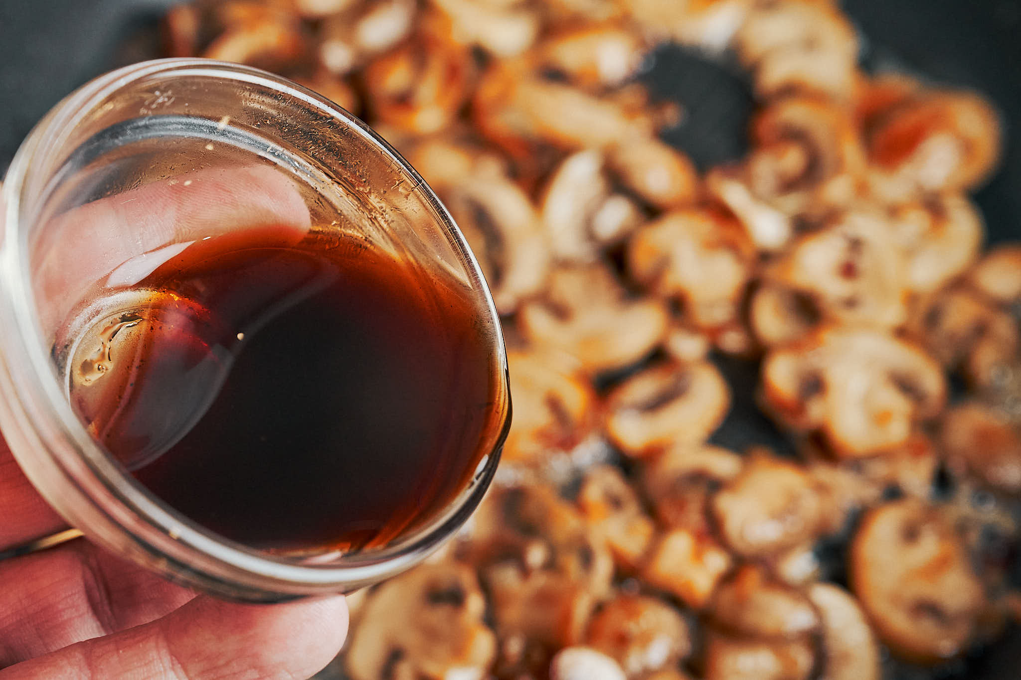 pouring Worcestershire sauce over golden mushrooms