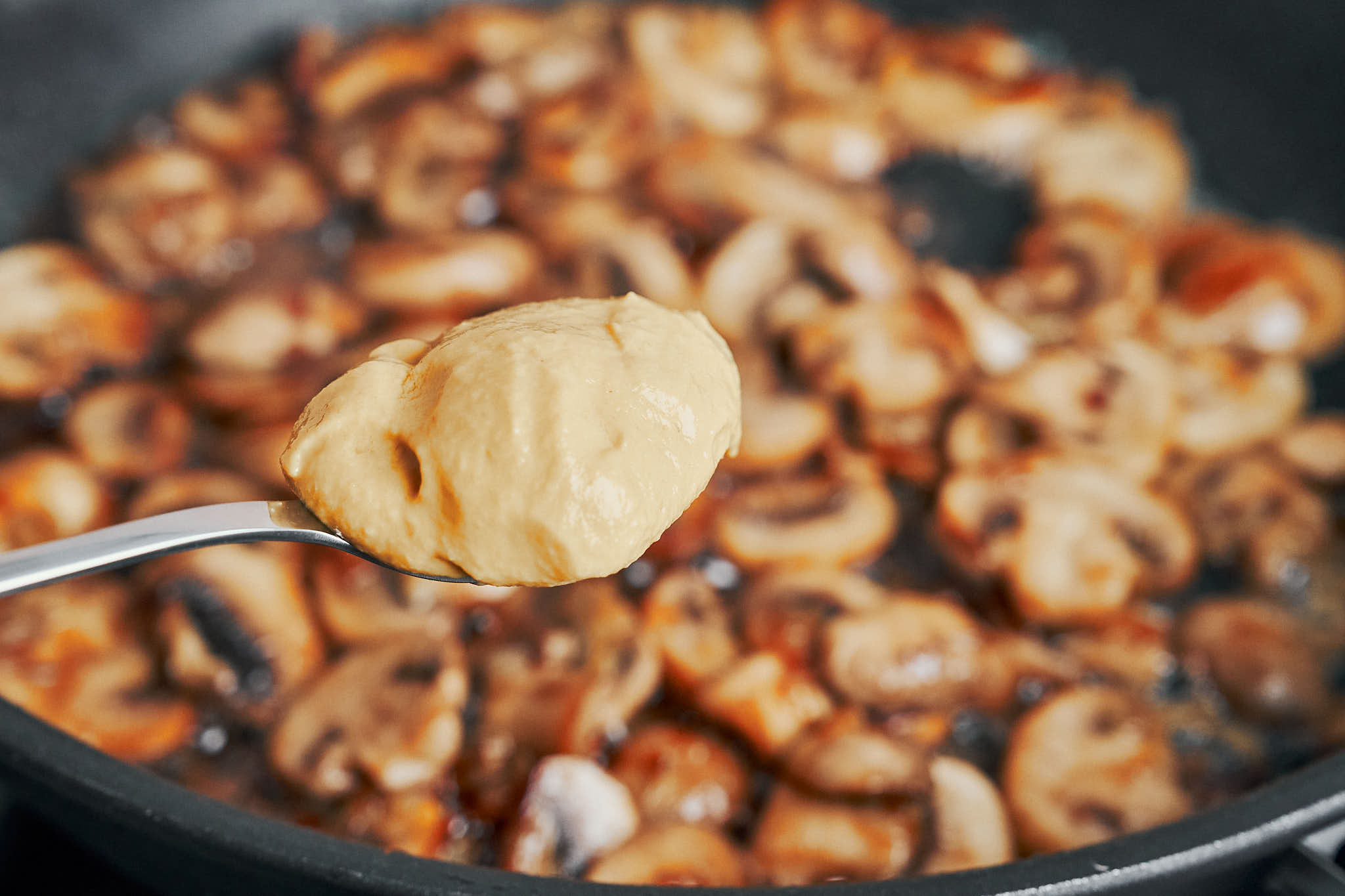 adding Dijon mustard to mushrooms in skillet