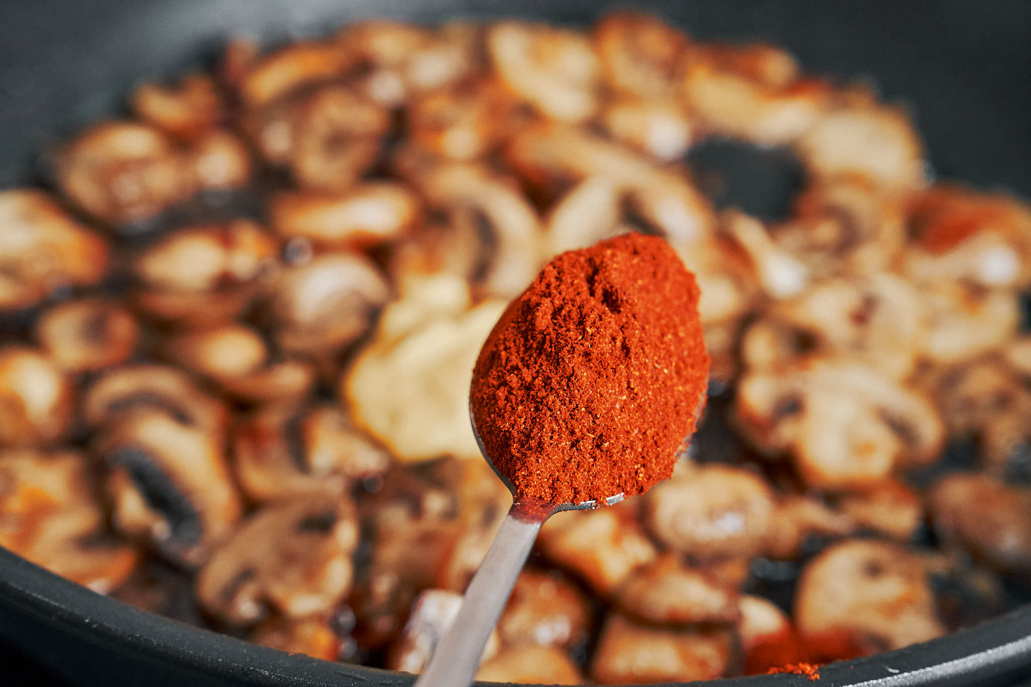 adding paprika to sautéed mushrooms in skillet