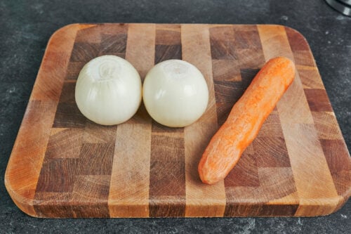 fresh onions and carrot on cutting board for pork stew