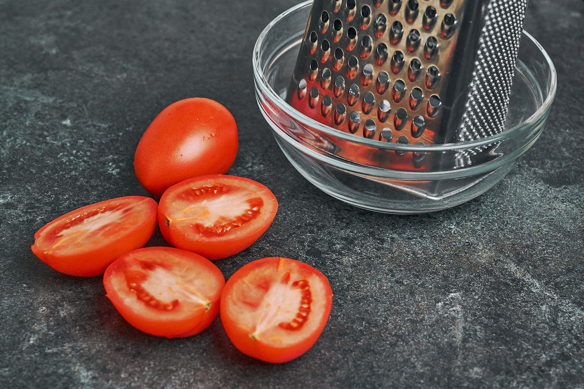 fresh tomatoes cut in half next to box grater